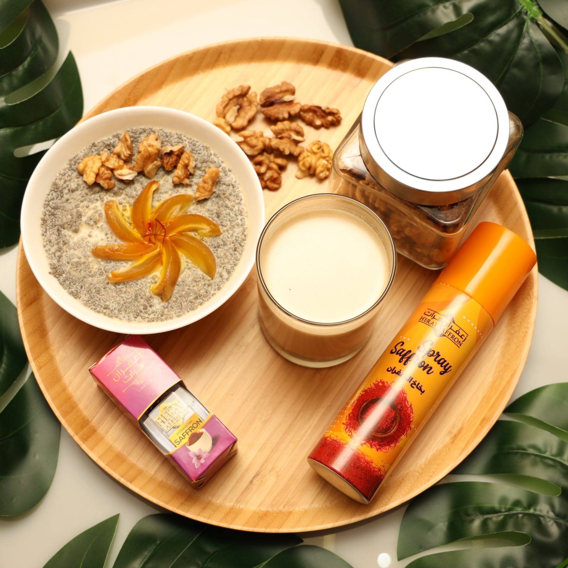 Wooden tray with chia pudding, nuts, a glass of milk, and a bottle on a leafy background
