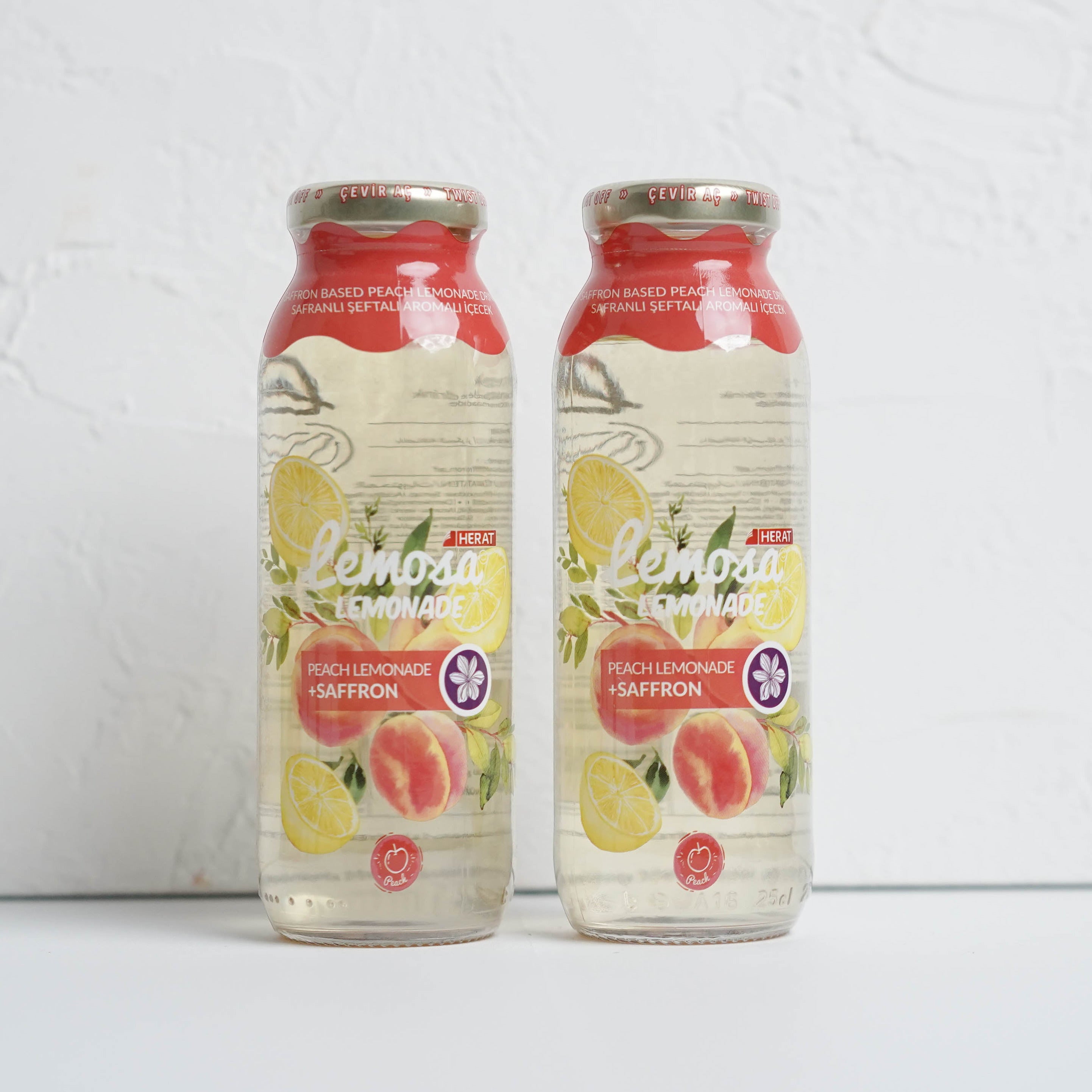 Two bottles of a beverage with a red label on a white background