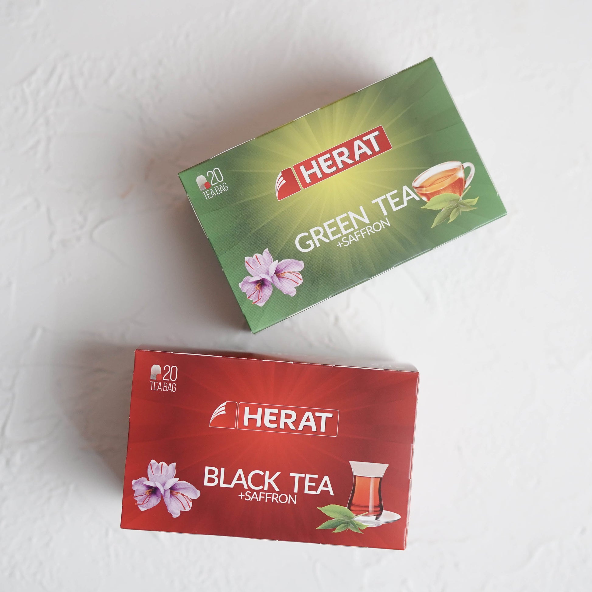 Two boxes of Herat tea, one green for green tea and one red for black tea, on a white background.