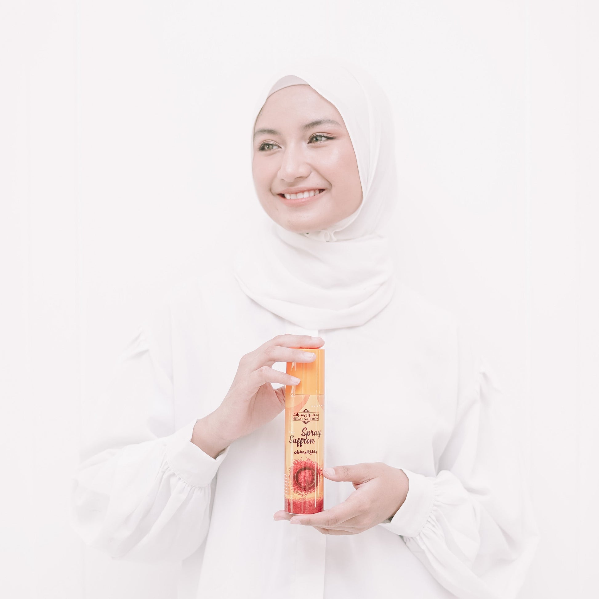 Woman in a white hijab holding a product against a white background