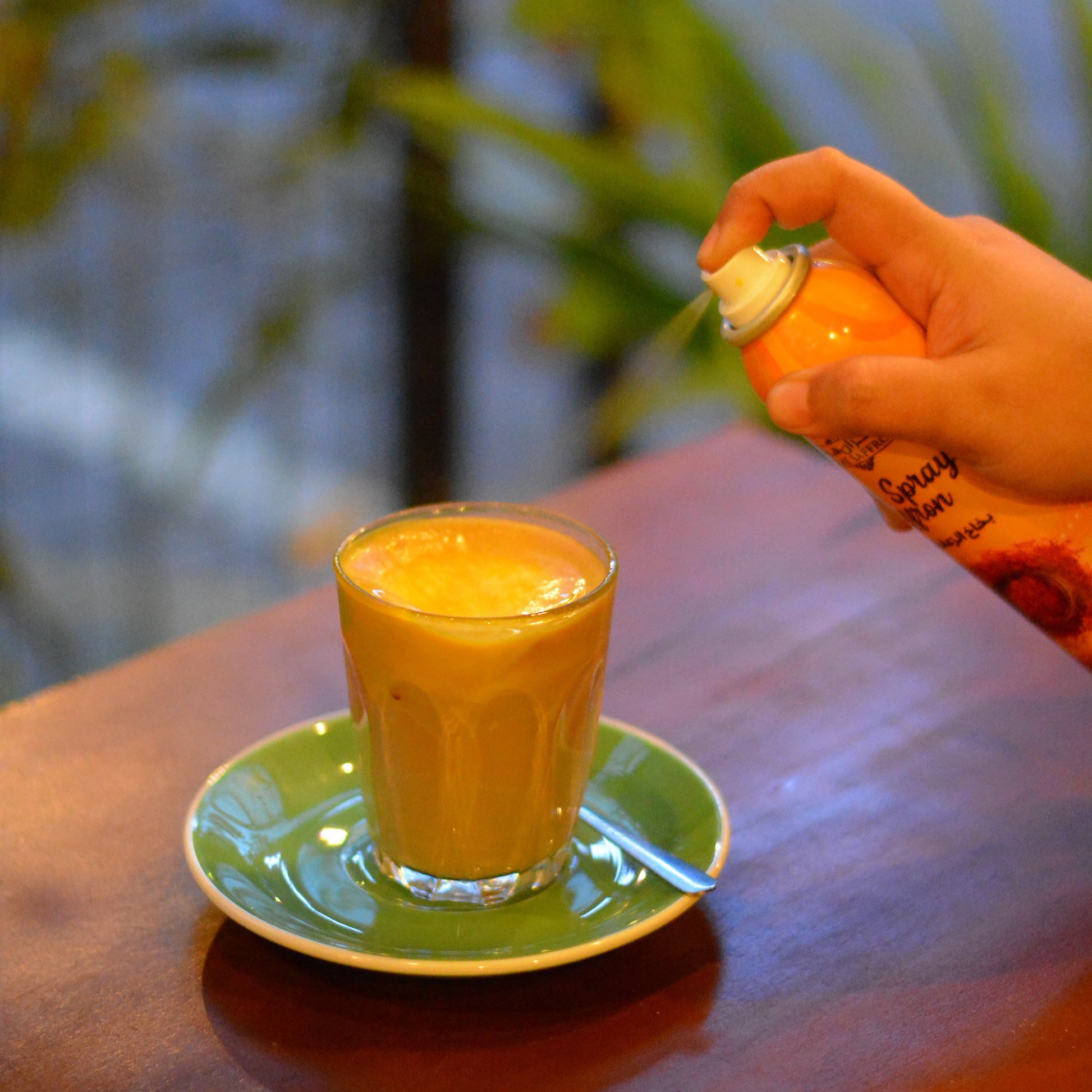 Person holding a small orange container near a larger green and orange object.