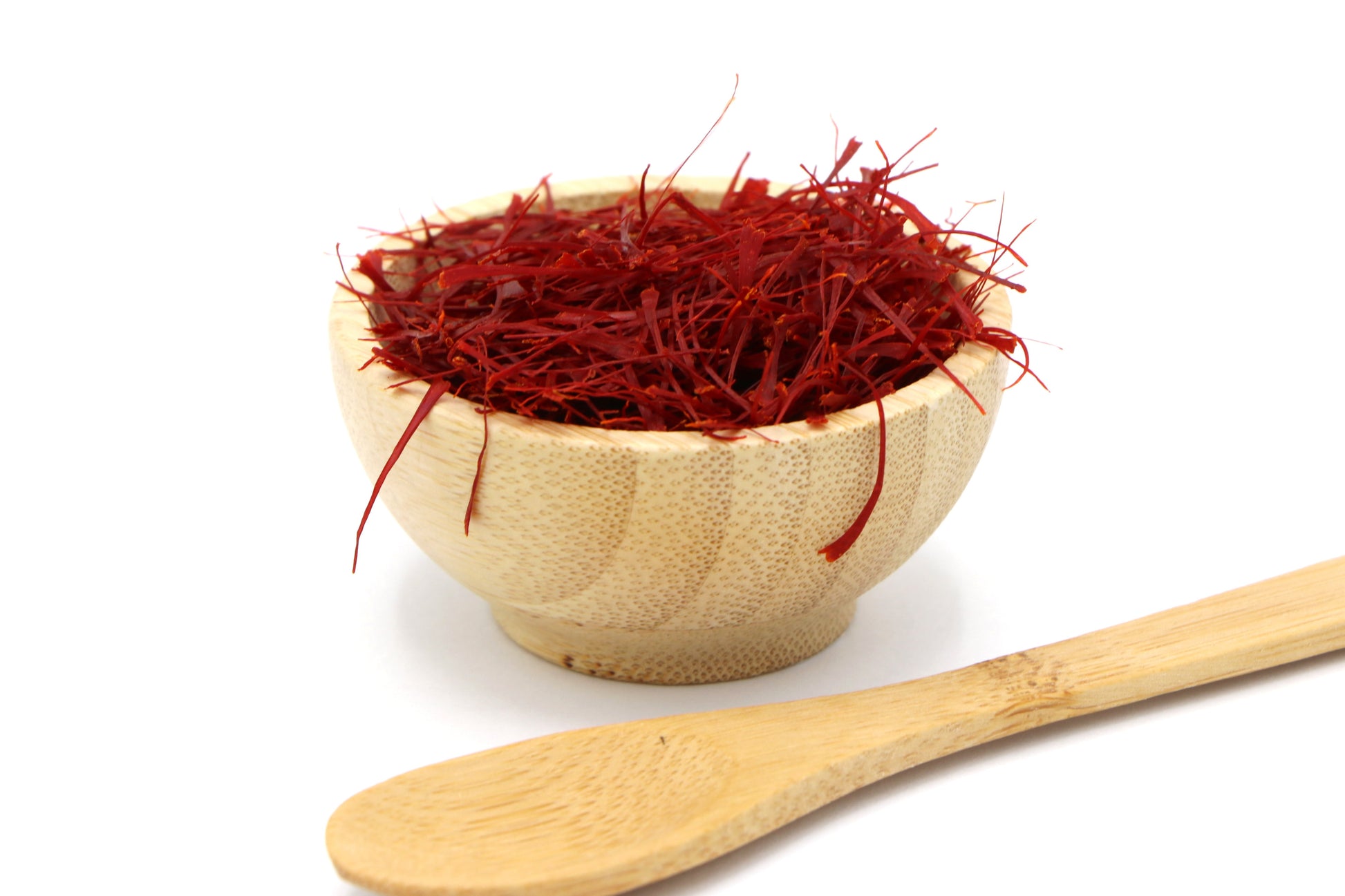 Red saffron threads in a beige bowl on a white background