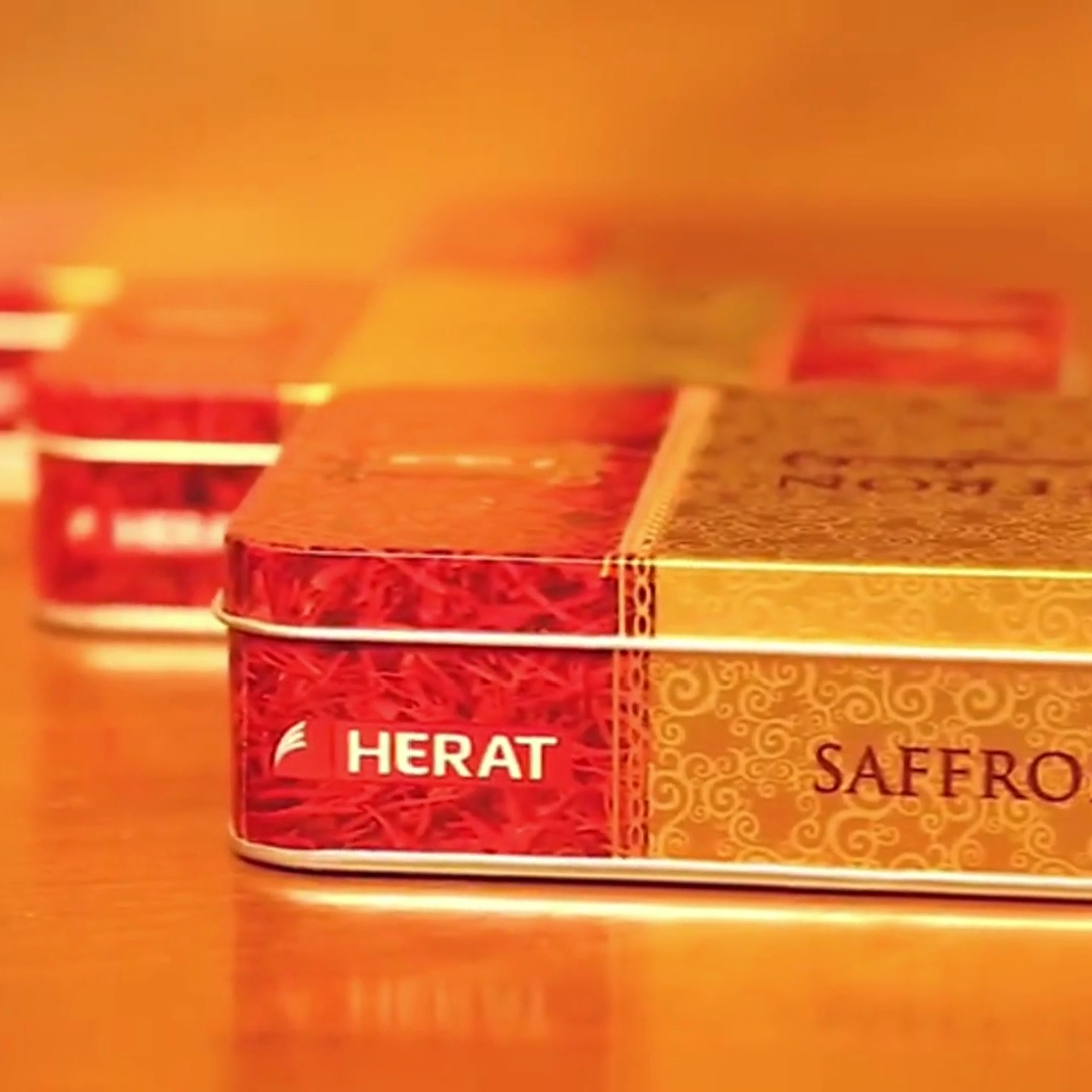 Herat Saffron packaging on a reflective surface with a warm color tone.
